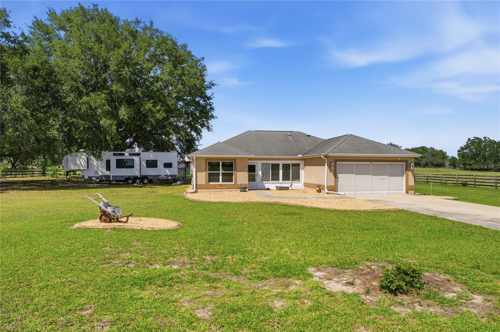 A single-story house with a two-car garage sits on a large, grassy lot — 7411 SE 180TH STREET, OXFORD, FL