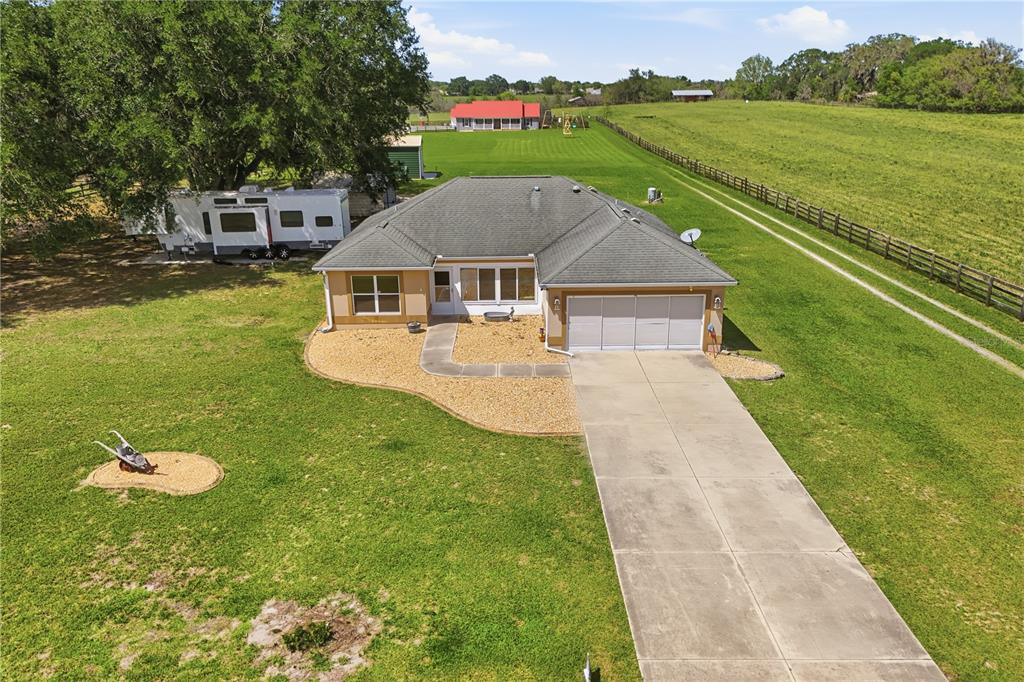 An aerial view shows a single-story house with a garage, driveway, and large grassy yard — 7411 SE 180TH STREET, OXFORD, FL