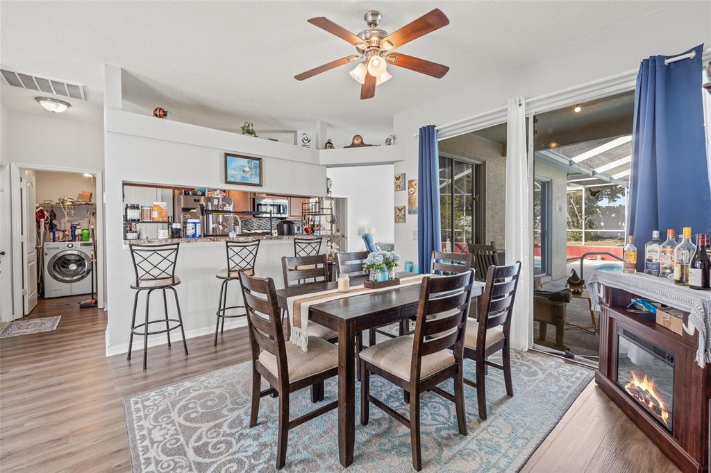 A dining area with a wooden table and chairs sits adjacent to a kitchen counter — 6401 GRAPEWOOD ROAD, SPRING HILL, FL