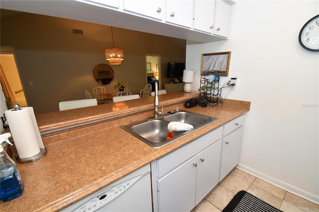 A kitchen features a double-basin sink, light-colored cabinets, and a pass-through window to the dining area — 1712 GLENHOUSE DRIVE UNIT GL417, SARASOTA, FL