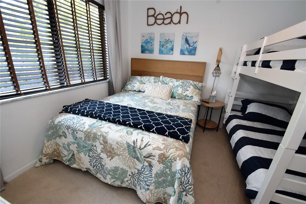 A bedroom features a double bed, a bunk bed, and coastal-themed wall decor — 1712 GLENHOUSE DRIVE UNIT GL417, SARASOTA, FL