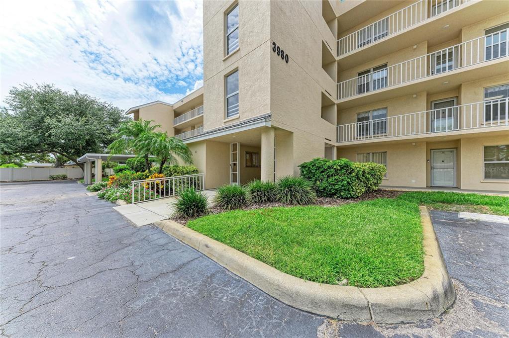 A multi-story apartment building exterior features a beige facade, balconies, and a landscaped front lawn — 3980 IRONWOOD CIRCLE UNIT 301, BRADENTON, FL