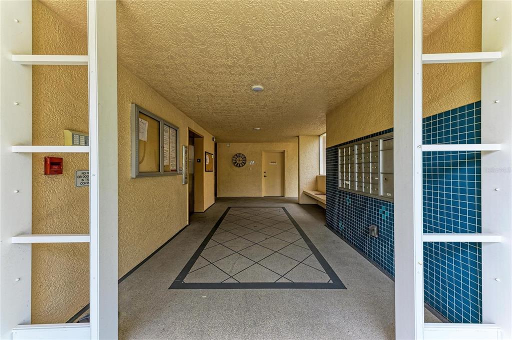 A building entrance hall features a tiled floor, mailboxes, and a bulletin board — 3980 IRONWOOD CIRCLE UNIT 301, BRADENTON, FL