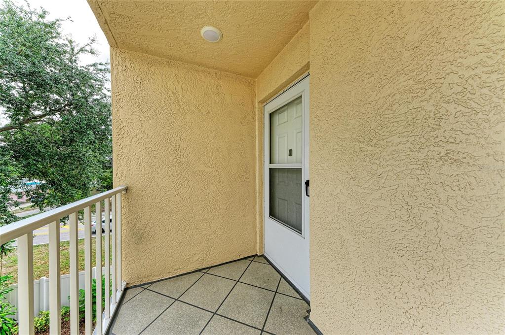 A small balcony with a white railing, tiled floor, and a white storm door — 3980 IRONWOOD CIRCLE UNIT 301, BRADENTON, FL