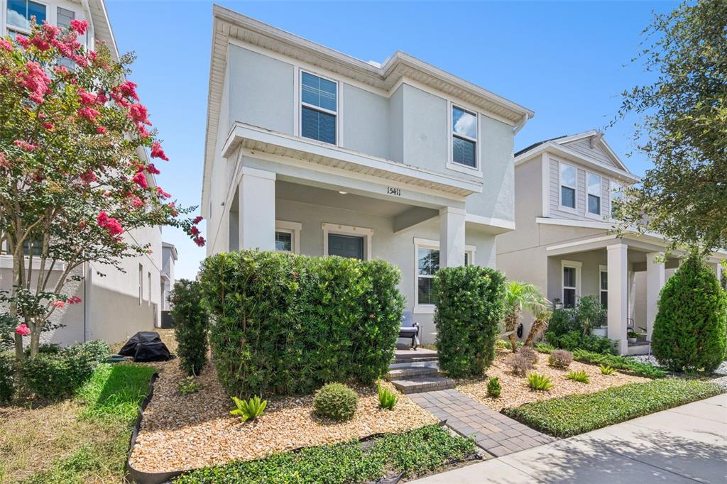 A two-story house with a front porch, a landscaped yard, and a paved walkway — 15411 GILLIGAN COURT, WINTER GARDEN, FL
