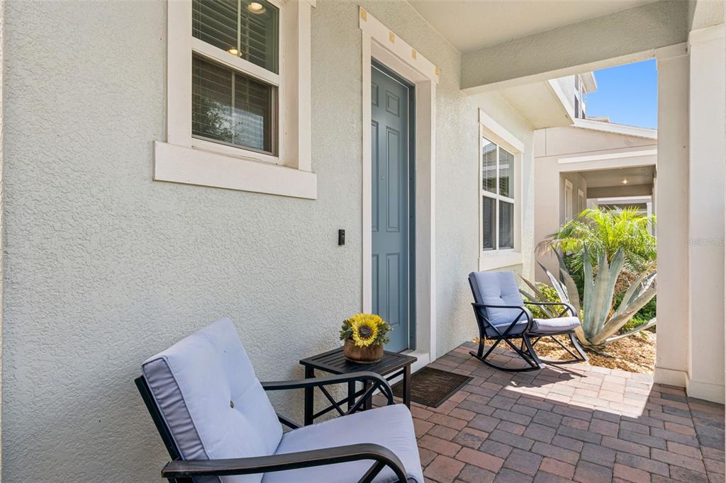 A covered front porch features two rocking chairs, a small table, and a blue door — 15411 GILLIGAN COURT, WINTER GARDEN, FL