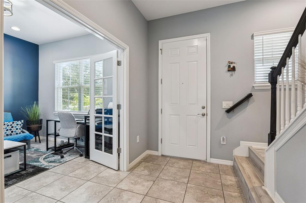 A tiled entryway features a white front door, a staircase, and a home office entrance — 15411 GILLIGAN COURT, WINTER GARDEN, FL