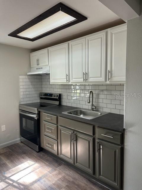 A kitchen features white upper cabinets, dark lower cabinets, a subway tile backsplash, and stainless appliances — 2122 BRADFORD STREET UNIT 521, CLEARWATER, FL