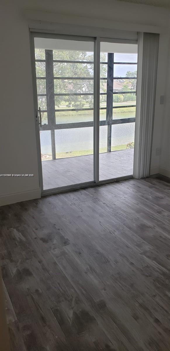 A room with light wood-look flooring features a sliding glass door opening to a screened patio — 9709 Hammocks Blvd # 202, Miami FL 33196, MIAMI, FL