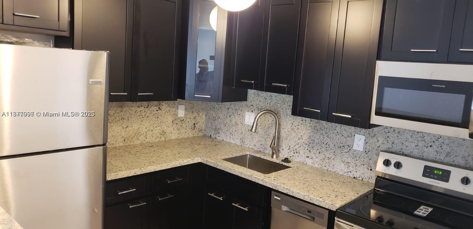 A kitchen features dark cabinets, granite countertops, stainless steel appliances, and a sink — 9709 Hammocks Blvd # 202, Miami FL 33196, MIAMI, FL