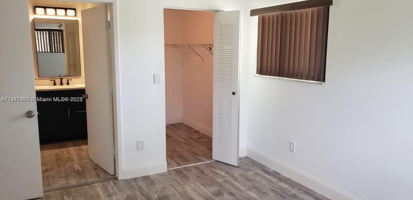 A bedroom features wood-look flooring, a walk-in closet, and an attached bathroom — 9709 Hammocks Blvd # 202, Miami FL 33196, MIAMI, FL
