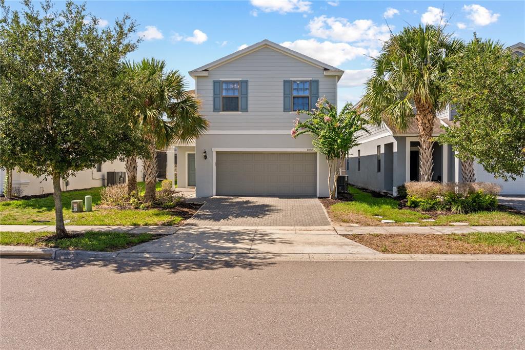 A two-story house with light gray siding, a two-car garage, and palm trees in front — 8904 PRAGUE WAY, KISSIMMEE, FL