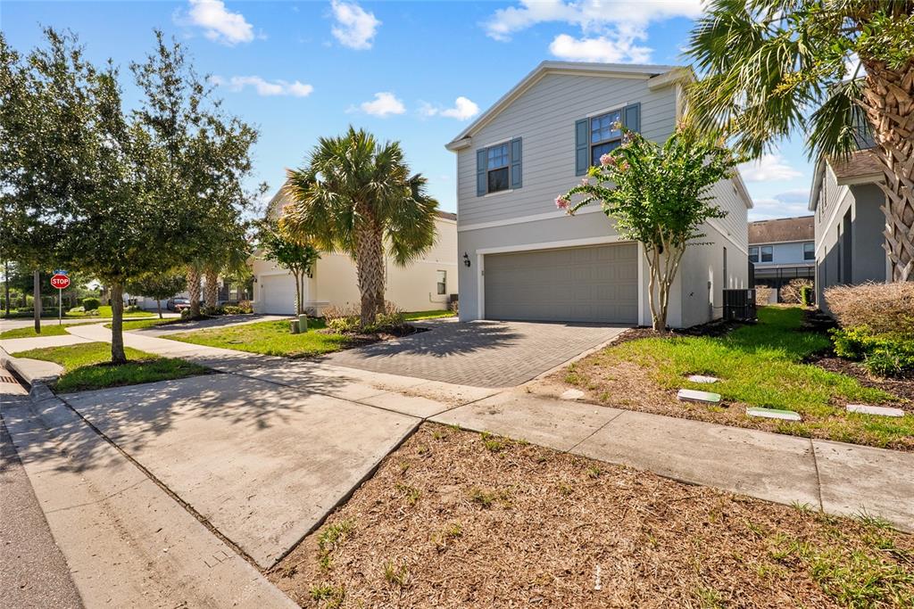 A two-story house with light blue siding, a gray garage door, and a paved driveway — 8904 PRAGUE WAY, KISSIMMEE, FL