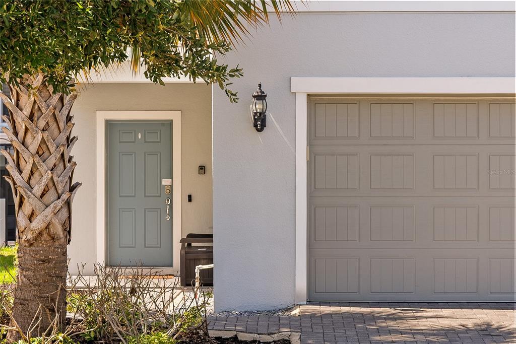 A light blue front door sits next to a gray garage door on a house exterior — 8904 PRAGUE WAY, KISSIMMEE, FL