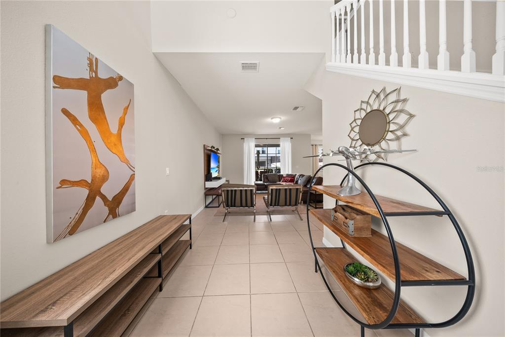 A bright entryway with tile flooring leads into a living area with a staircase — 8904 PRAGUE WAY, KISSIMMEE, FL