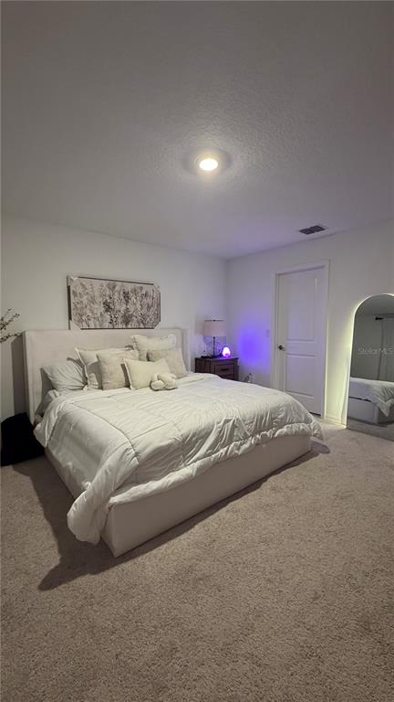 A bedroom features a large bed with white bedding, a nightstand, and an arched floor mirror — 2966 CANARY AVENUE, DAVENPORT, FL