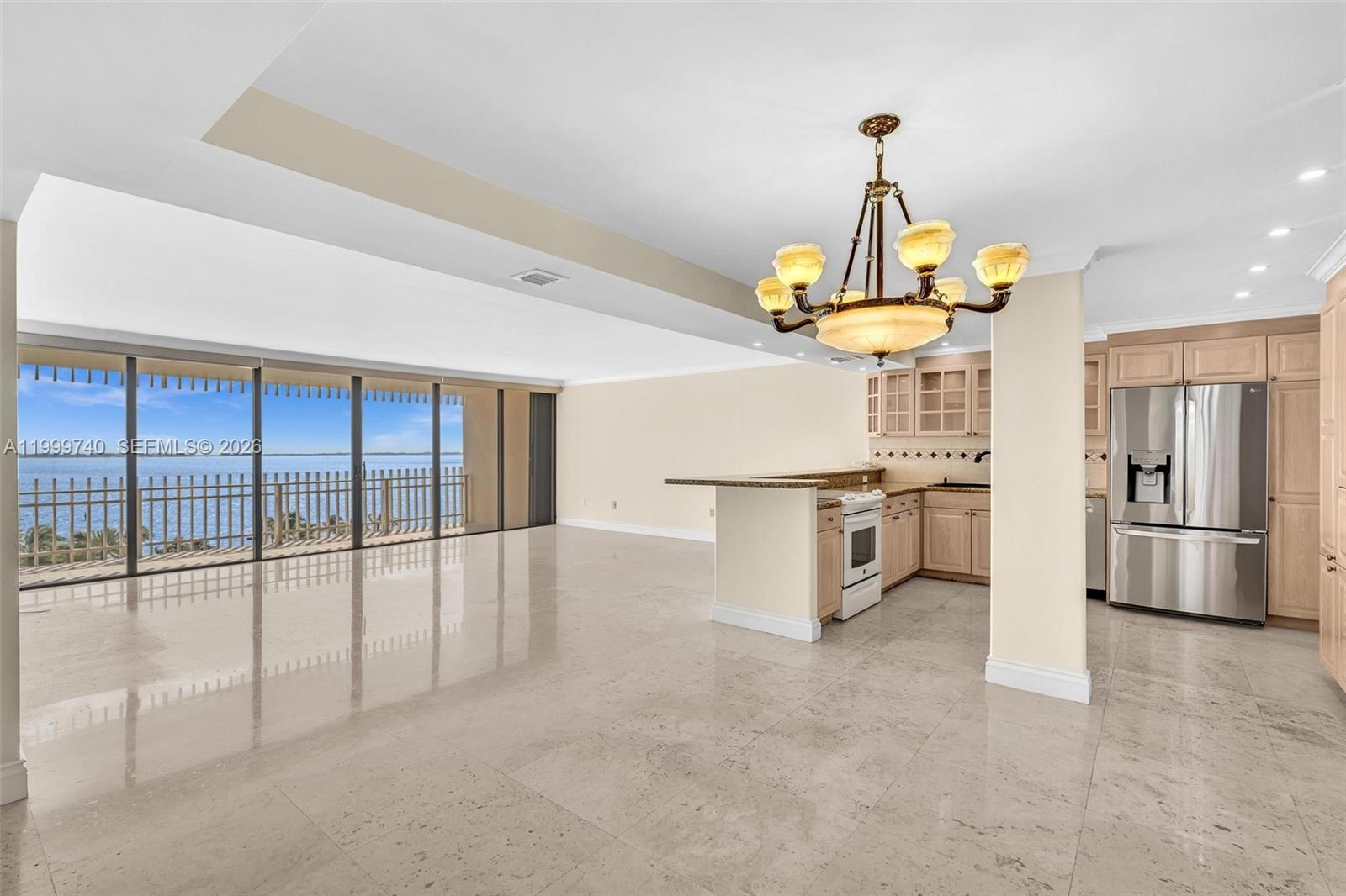 An open-concept kitchen and living area features light tile floors and a waterfront balcony — 2 Grove Isle Dr # B805, Miami FL 33133, MIAMI, FL