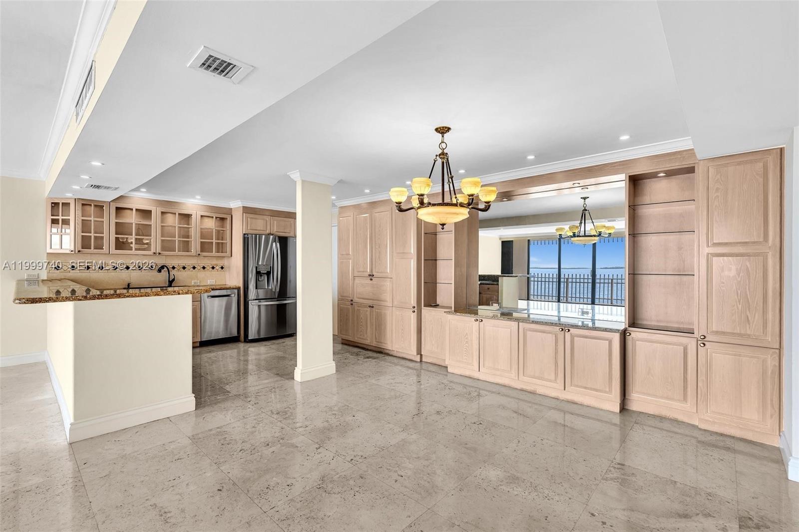 A kitchen and dining area with light wood cabinetry, granite countertops, and tile flooring — 2 Grove Isle Dr # B805, Miami FL 33133, MIAMI, FL