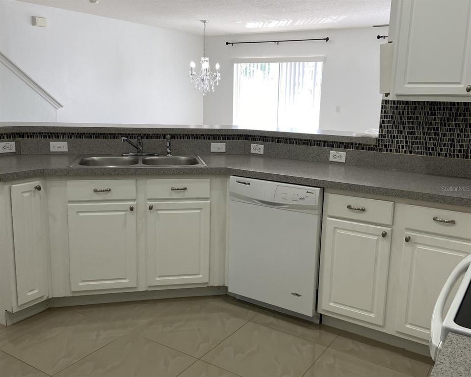 A kitchen features white cabinets, a double sink, a dishwasher, and a tiled floor — 2444 HASSONITE STREET, KISSIMMEE, FL