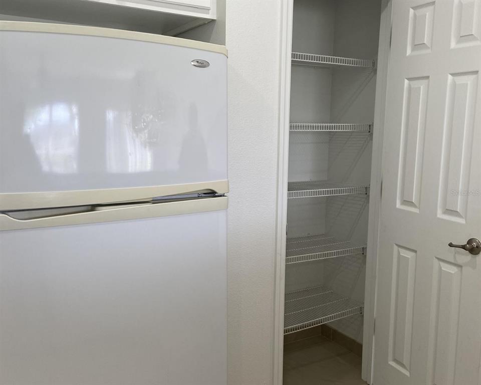 A white refrigerator stands next to an open pantry with wire shelving — 2444 HASSONITE STREET, KISSIMMEE, FL