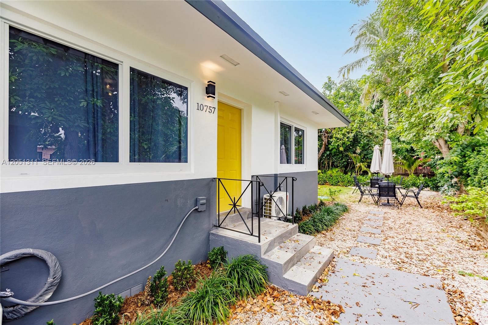 A single-story house features a yellow front door, gray lower siding, and a small patio — 10757 NE 2 Ct # 0, Miami FL 33161, MIAMI, FL