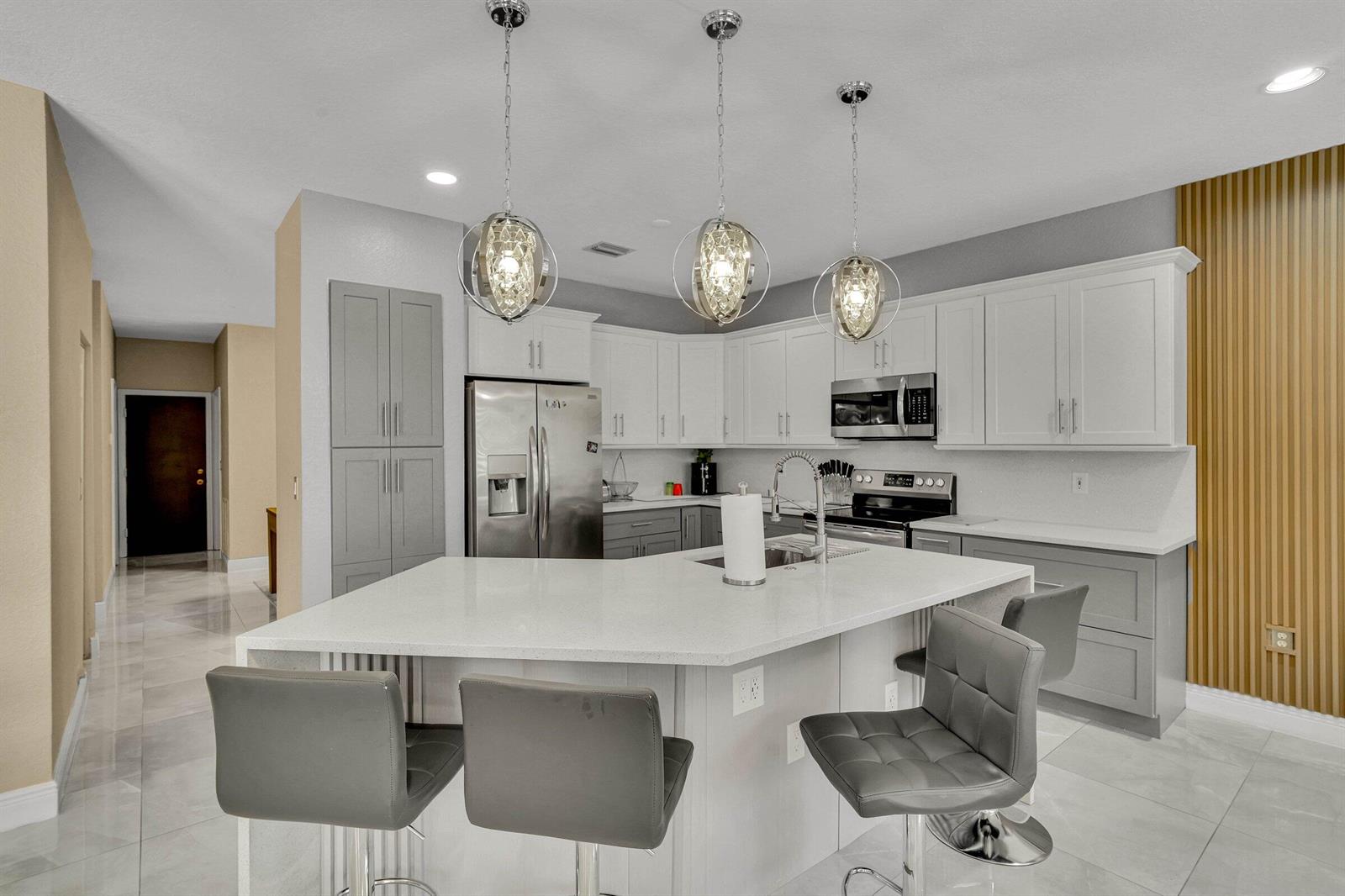 A modern kitchen features a white quartz island, gray cabinetry, and three spherical pendant lights — 16254 SW 18th Place, Miramar FL 33027, MIRAMAR, FL