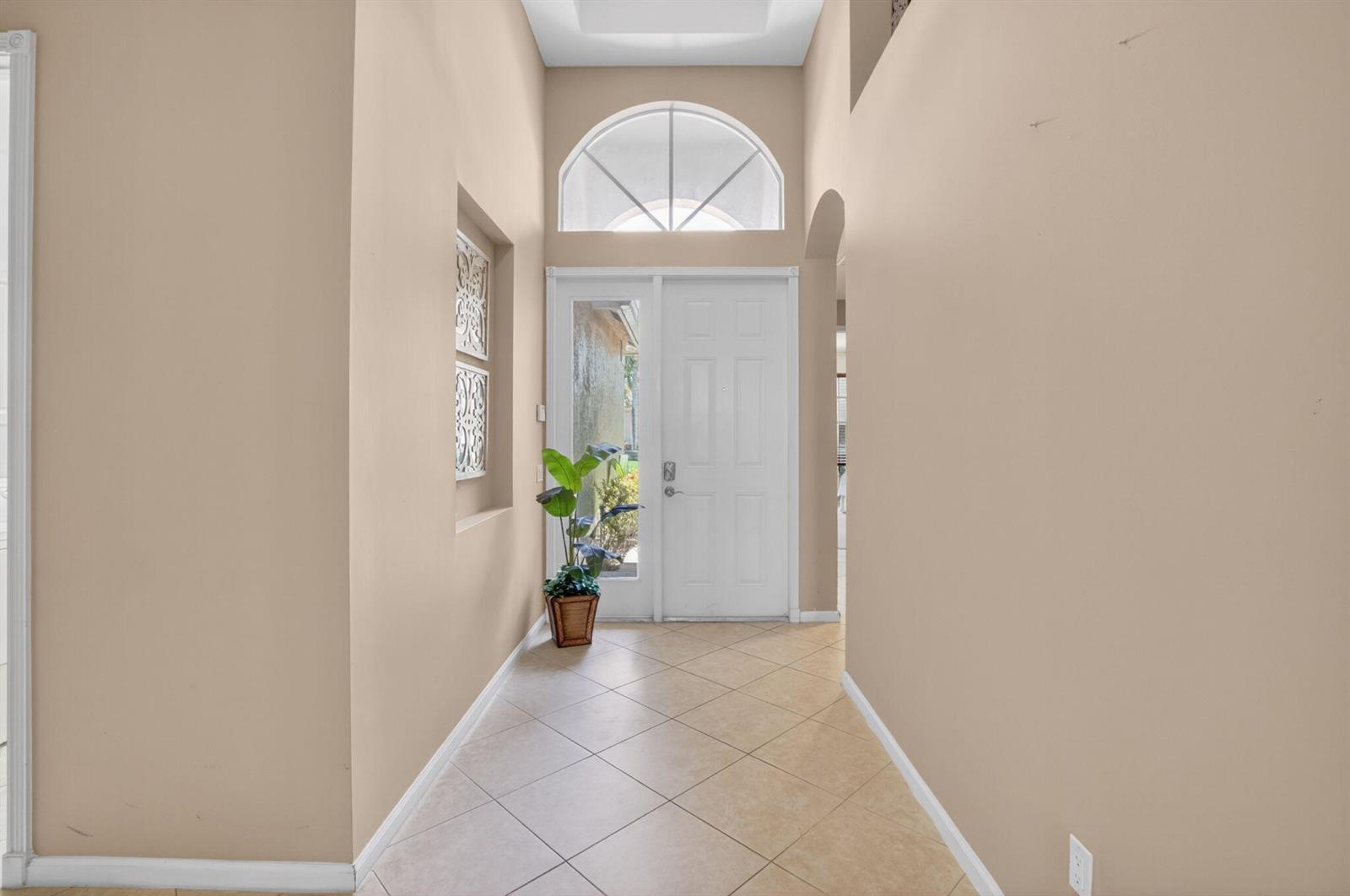 A tiled entryway features a high ceiling, a white front door, and a decorative window — 6959 Imperial Beach Circle, Delray Beach FL 33446, DELRAY BEACH, FL