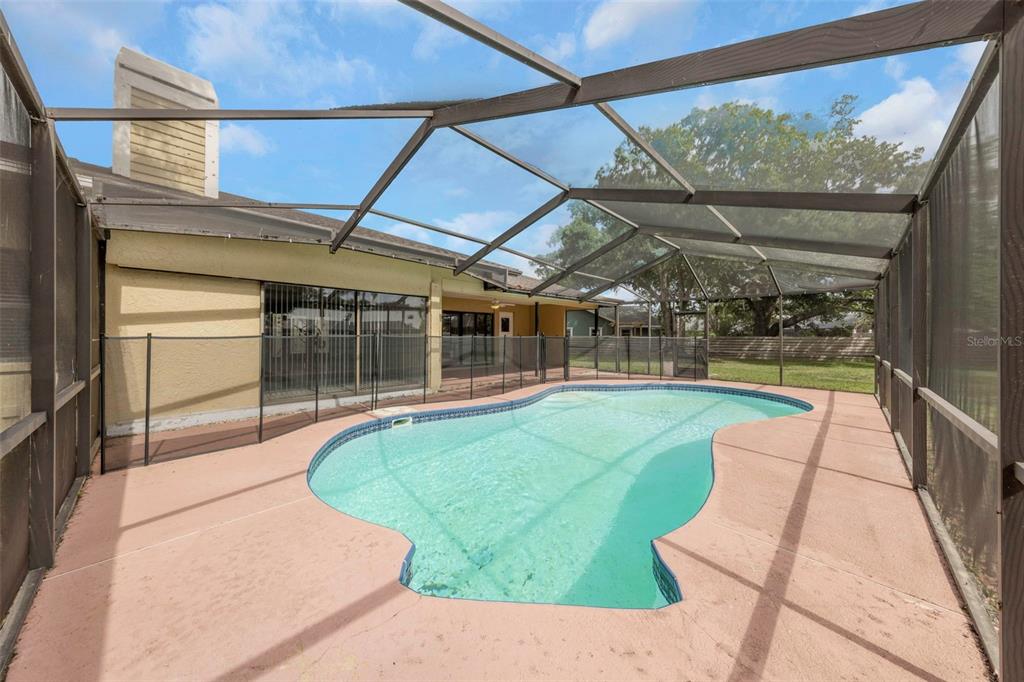 A swimming pool with a safety fence is enclosed by a screened lanai — 3334 BRIAN ROAD N, PALM HARBOR, FL