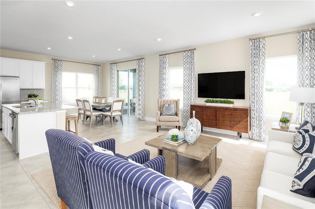An open-concept living and dining area features a kitchen island, tile flooring, and neutral decor — 2441 WHITE LADYFISH ROAD, WIMAUMA, FL