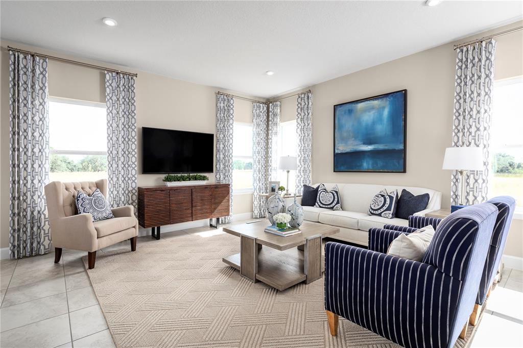 A living room features a television, a sofa, armchairs, and a coffee table on tile — 2441 WHITE LADYFISH ROAD, WIMAUMA, FL