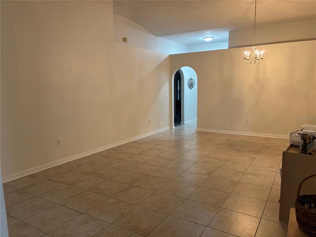 An empty room with beige walls, tile flooring, and an arched doorway leading to another area — 304 MARION OAKS TRAIL, OCALA, FL