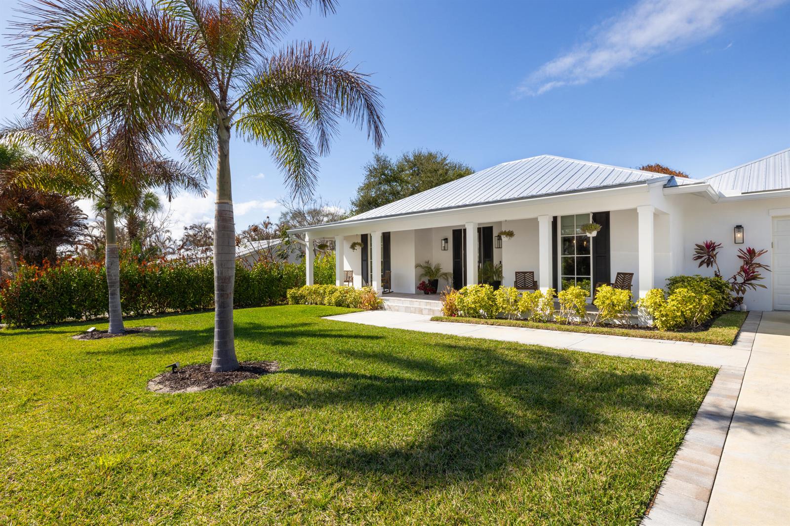 A white single-story house with a metal roof, front porch, and palm trees in the yard — 5169 SE Horseshoe Point Road, Stuart FL 34997, STUART, FL