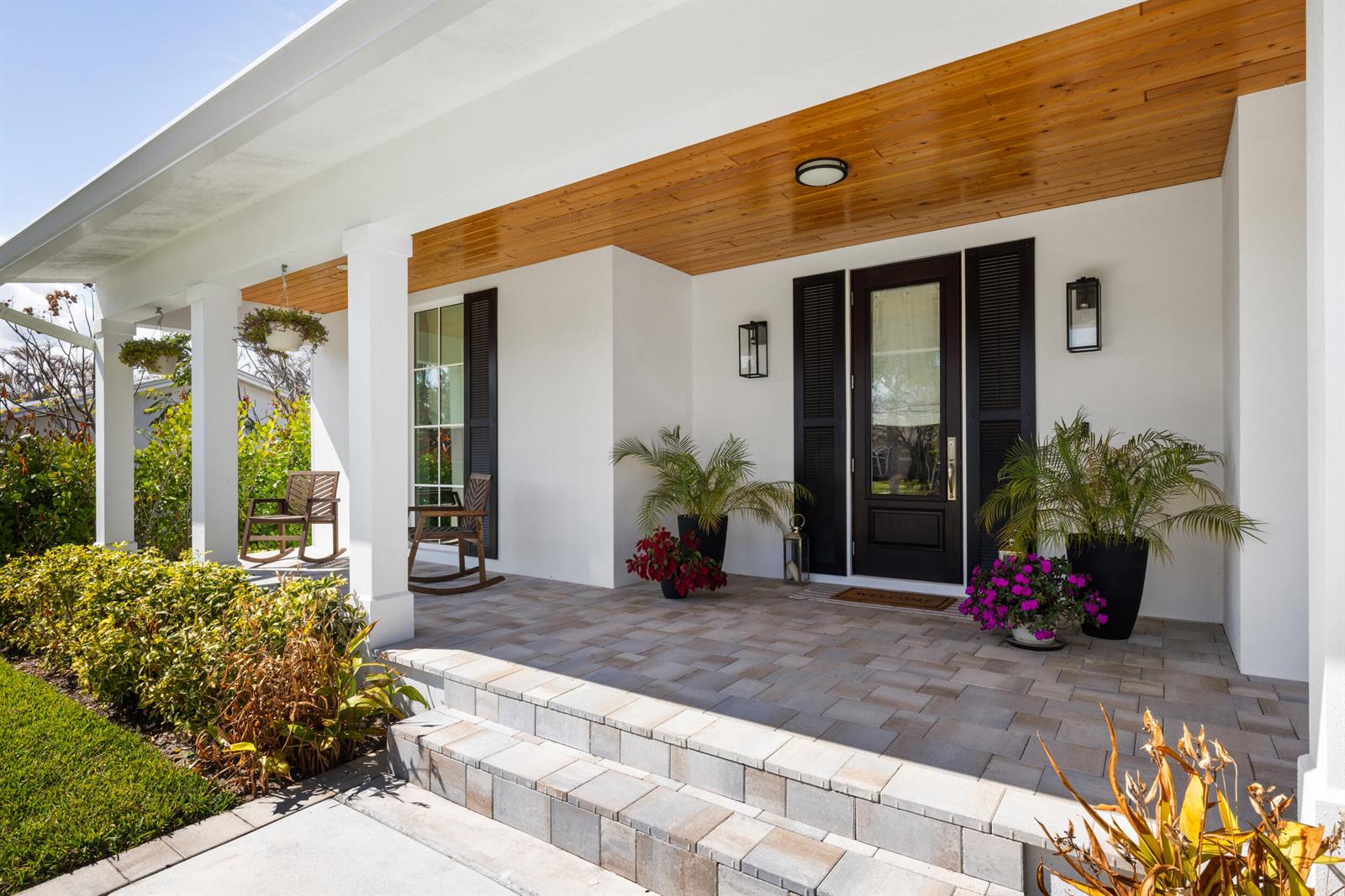 A front porch with a wood-paneled ceiling, white columns, and a dark front door — 5169 SE Horseshoe Point Road, Stuart FL 34997, STUART, FL