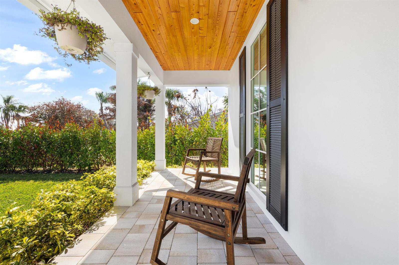 A covered porch features two wooden rocking chairs, a wood-paneled ceiling, and white exterior walls — 5169 SE Horseshoe Point Road, Stuart FL 34997, STUART, FL