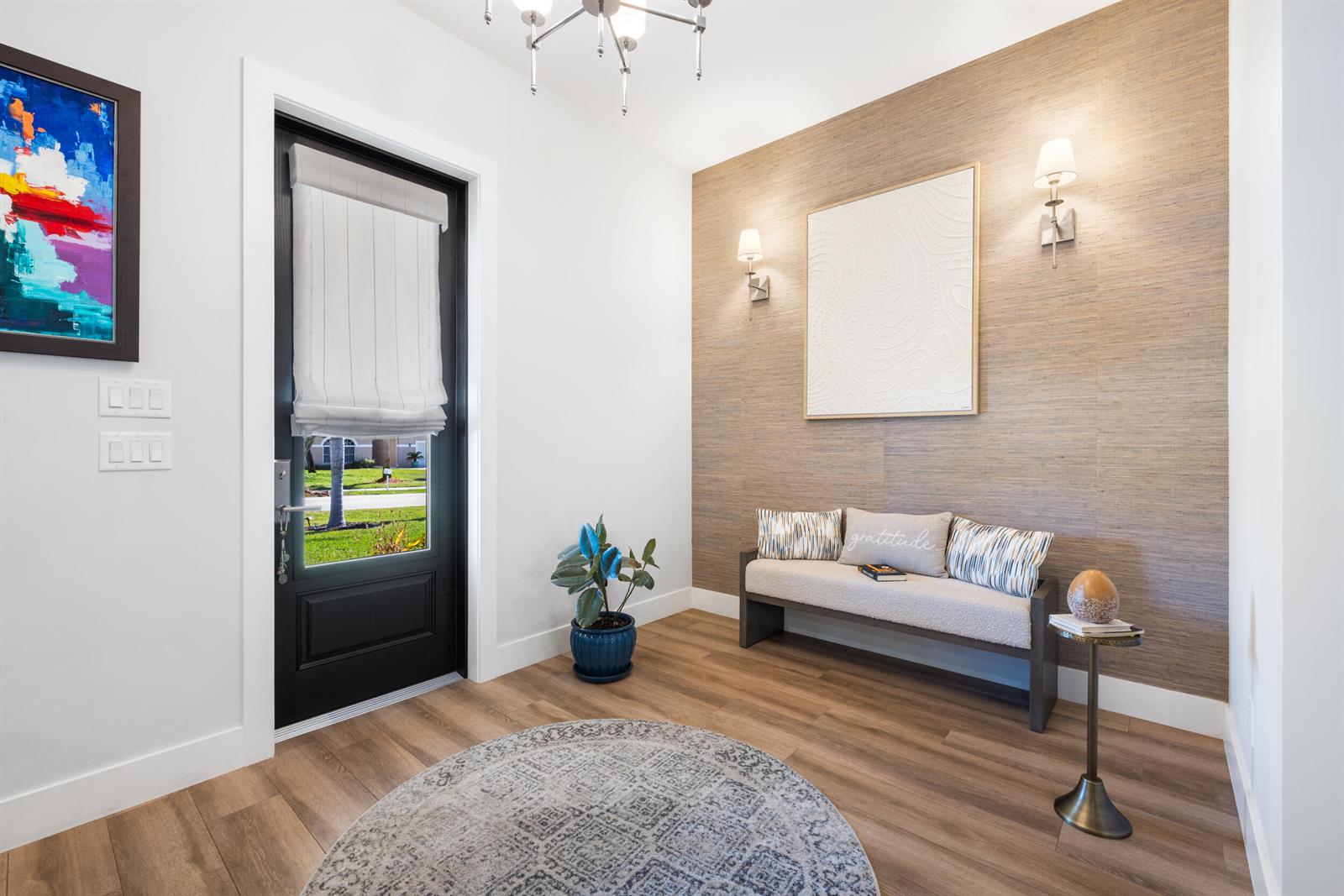 An entryway features a textured accent wall, a bench, a round rug, and a front door — 5169 SE Horseshoe Point Road, Stuart FL 34997, STUART, FL