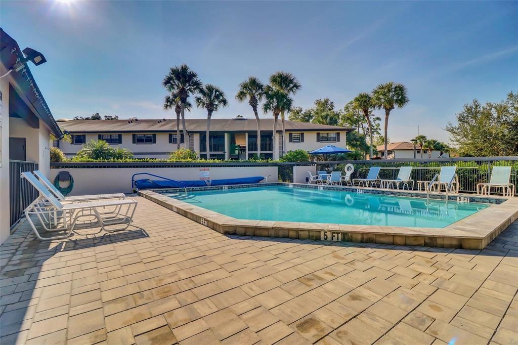 A rectangular swimming pool with lounge chairs sits on a paved patio near an apartment building — 1515 FORREST NELSON BOULEVARD UNIT N104, PORT CHARLOTTE, FL
