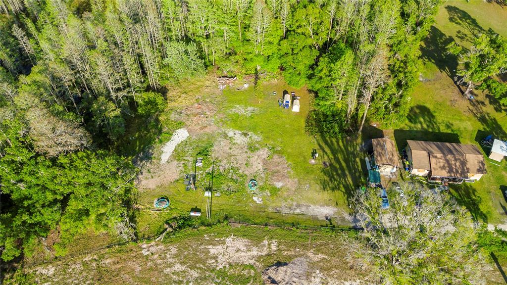An aerial view shows a house, a shed, and a large grassy lot with trees — 4436 JOY DRIVE, LAND O LAKES, FL