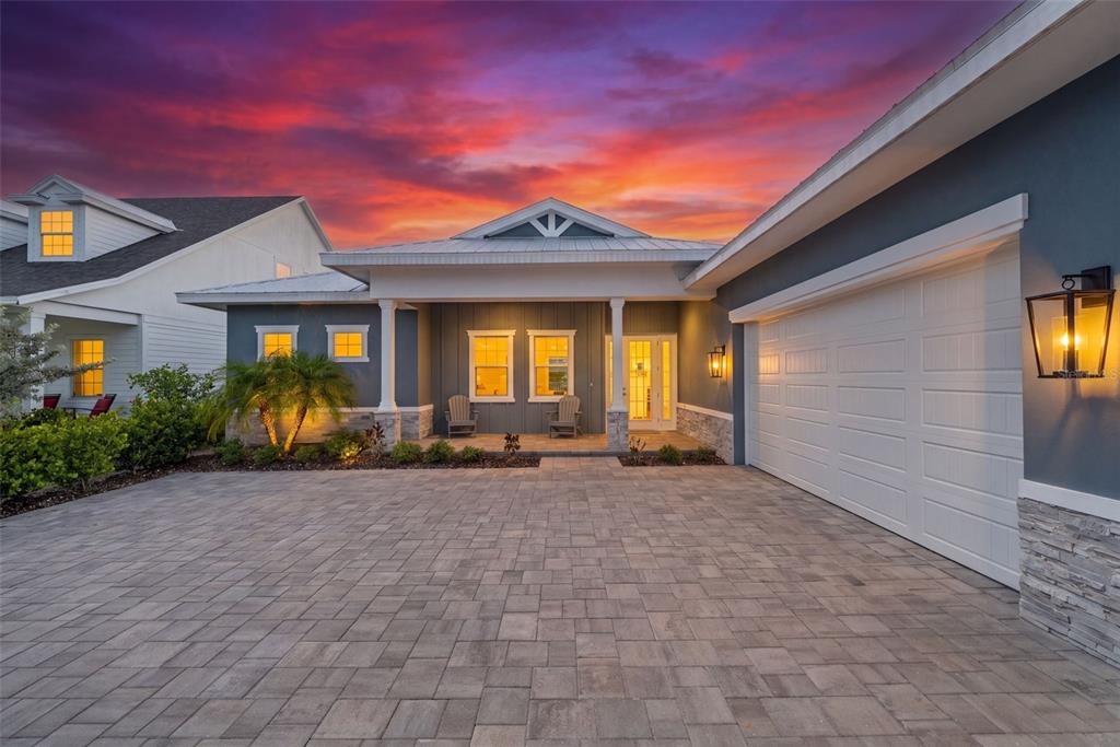 A single-story house with a paved driveway, garage, and front porch at sunset — 42231 LAKE TIMBER DRIVE, PUNTA GORDA, FL