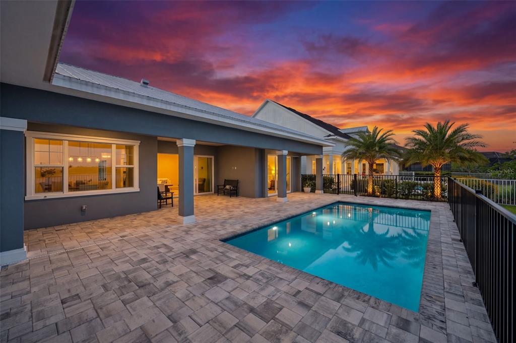 A backyard patio with a rectangular swimming pool and a view of a sunset sky — 42231 LAKE TIMBER DRIVE, PUNTA GORDA, FL
