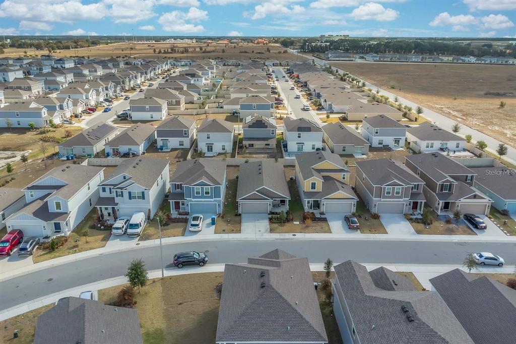 An aerial view shows a suburban neighborhood with rows of single-family homes and streets — 1513 CUMBERLAND AVENUE, DAVENPORT, FL