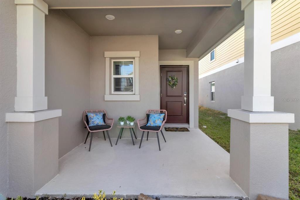 A covered front porch features two chairs, a small table, and a brown front door — 1513 CUMBERLAND AVENUE, DAVENPORT, FL