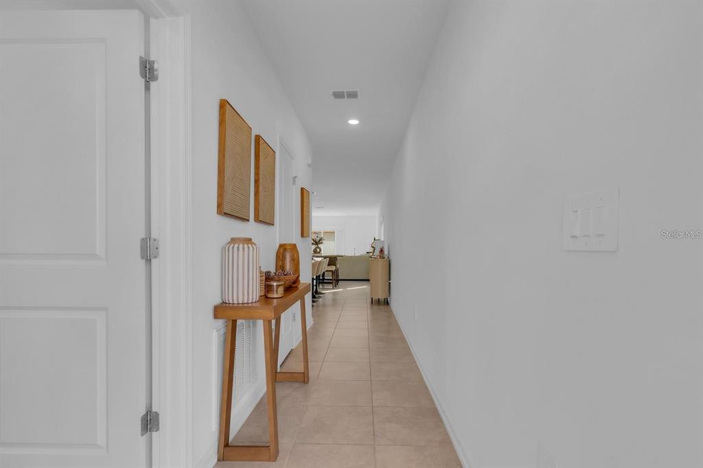 A bright hallway with tile flooring leads to an open living area with neutral walls — 1513 CUMBERLAND AVENUE, DAVENPORT, FL
