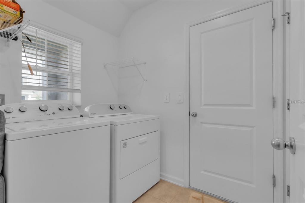 A laundry room features white appliances, a window with blinds, and a white door — 1513 CUMBERLAND AVENUE, DAVENPORT, FL