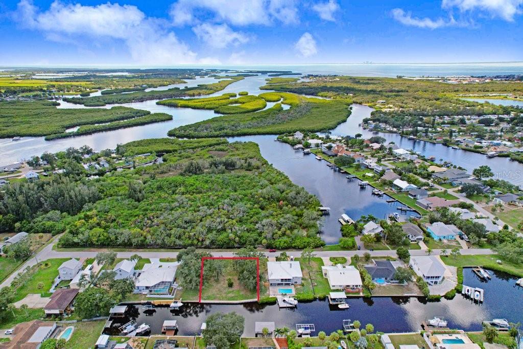 An aerial view shows a vacant waterfront lot outlined in red between two residential houses — 406 14TH STREET SW, RUSKIN, FL