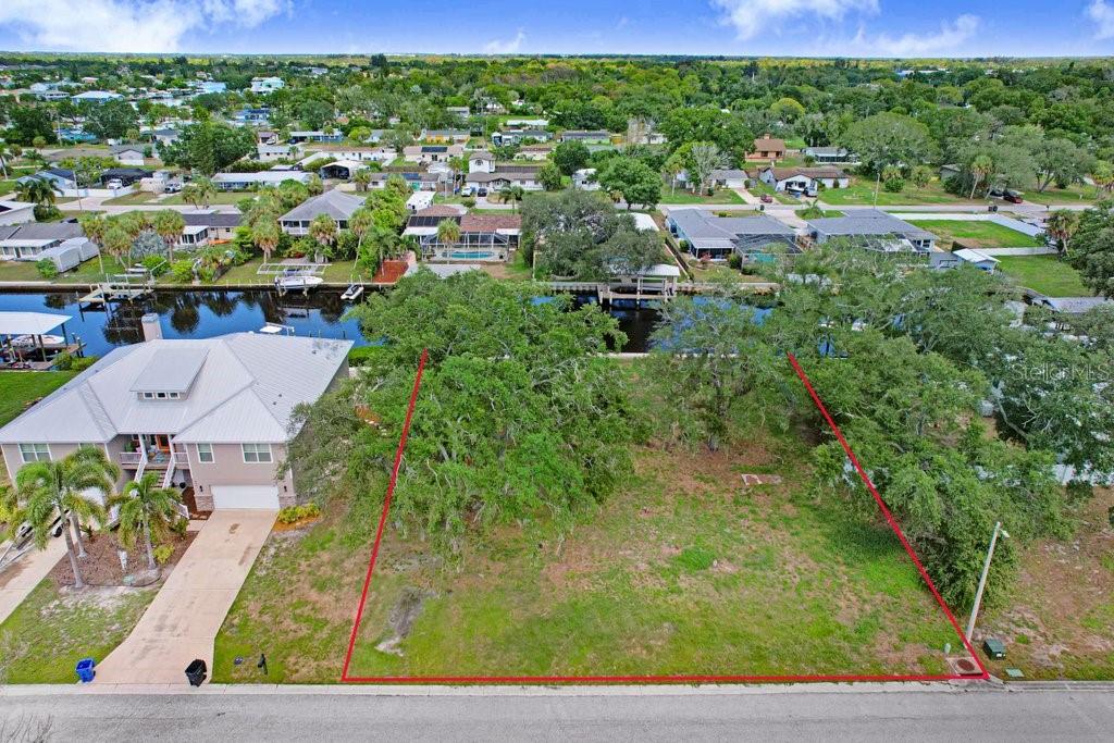 An aerial view shows a vacant, tree-covered residential lot outlined in red next to a house — 406 14TH STREET SW, RUSKIN, FL