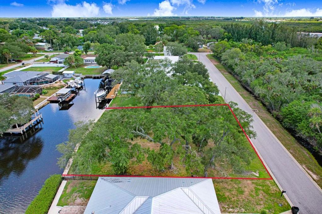 An aerial view shows a vacant, tree-covered waterfront lot outlined in red next to a road — 406 14TH STREET SW, RUSKIN, FL