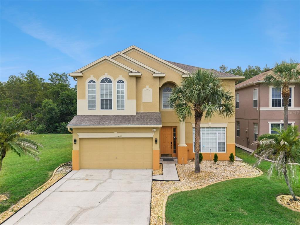 A two-story tan house with a two-car garage, palm trees, and a concrete driveway — 1860 WHITE HERON BAY CIRCLE, ORLANDO, FL