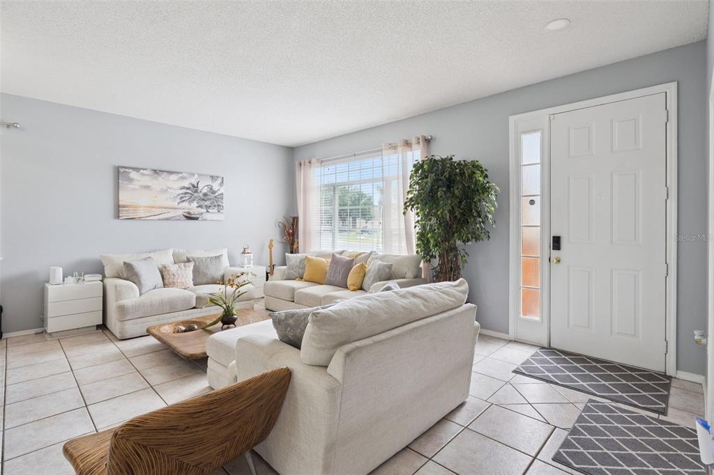 A living room with light gray walls, tile flooring, white sofas, and a front door — 1860 WHITE HERON BAY CIRCLE, ORLANDO, FL
