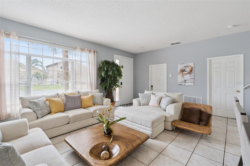A living room features light-colored sofas, a wooden coffee table, tile flooring, and large windows — 1860 WHITE HERON BAY CIRCLE, ORLANDO, FL