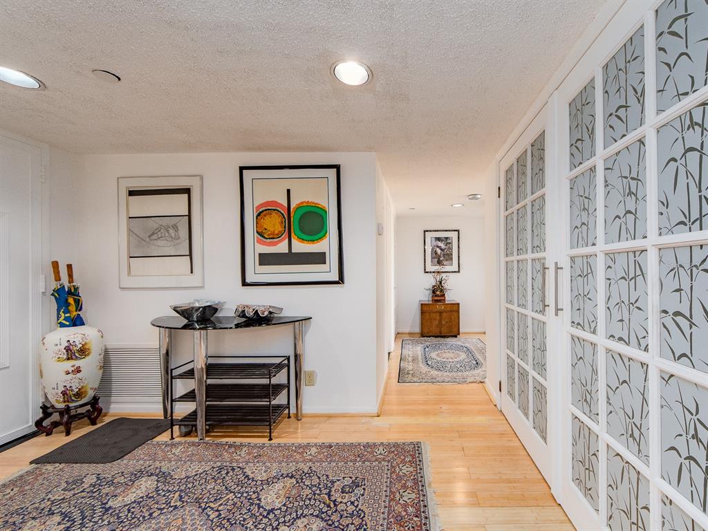 An entryway features hardwood floors, two area rugs, a console table, and glass-paned sliding doors — 1480 GULF BOULEVARD UNIT 612, CLEARWATER BEACH, FL